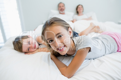 Portrait of smiling girl and boy lying on bed in bedroom