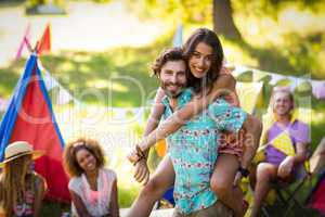 Man carrying woman on piggyback at campsite