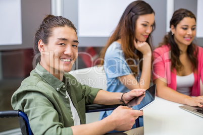 Portrait of smiling disabled executive using digital tablet in conference room