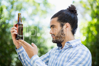 Man looking at beer bottle in the park