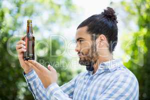 Man looking at beer bottle in the park
