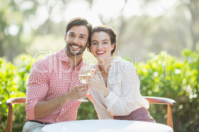 Couple toasting wine glasses while sitting in restaurant