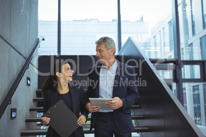Business executives smiling while looking at each other on stairs