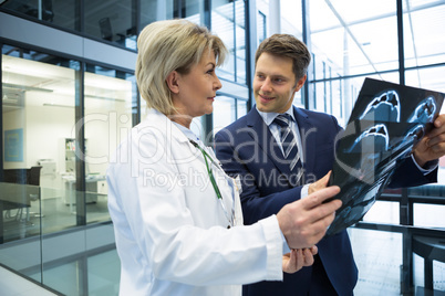 Female doctor discussing x-ray report with businessman