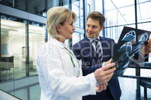 Female doctor discussing x-ray report with businessman