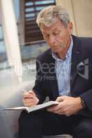 Attentive businessman writing in organizer