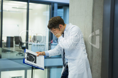 Upset male doctor standing near corridor