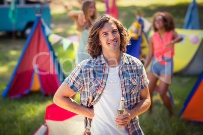 Portrait of man holding beer bottle at campsite