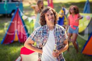 Portrait of man holding beer bottle at campsite