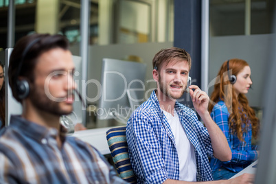 Portrait of male customer service executive talking on headset at desk