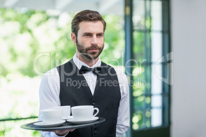 Male waiter holding tray with coffee cups