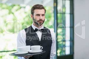 Male waiter holding tray with coffee cups