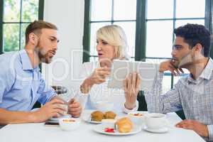 Executives discussing over digital tablet in a restaurant