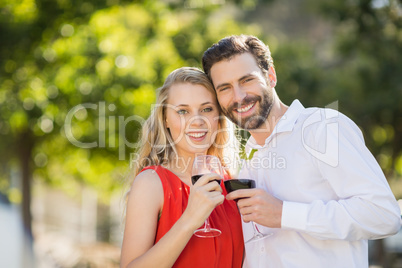 Happy couple holding wine glasses in the park