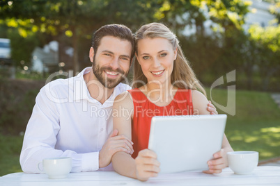 Happy couple smiling while holding digital tablet