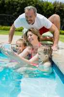 Smiling woman taking selfie with family in swimming pool