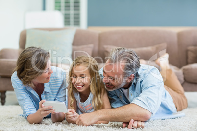 Family taking selfie from mobile phone while lying together on carpet in living room