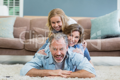 Portrait of happy family lying heaped on carpet in living room
