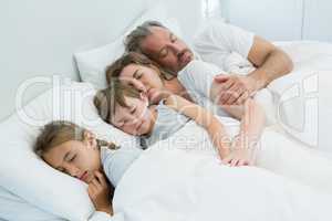 Family sleeping together in bed