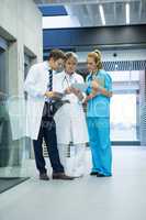 Medical team discussing over digital tablet in corridor