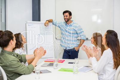 Executives appreciating their colleague during presentation in conference room