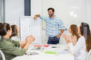 Executives appreciating their colleague during presentation in conference room