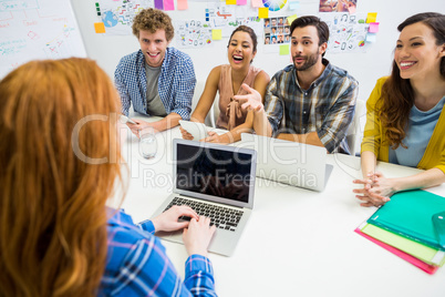 Colleagues discussing over laptop with executive during meeting