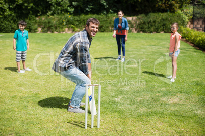 Happy family playing cricket in park
