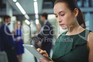 Female executive using digital tablet in corridor