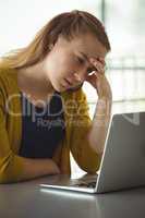 Sad schoolgirl looking at laptop in library