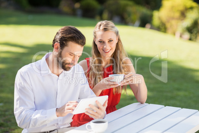 Happy couple having coffee and using digital tablet