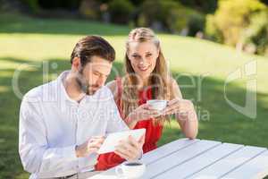 Happy couple having coffee and using digital tablet