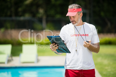 Swim coach looking at clipboard near poolside
