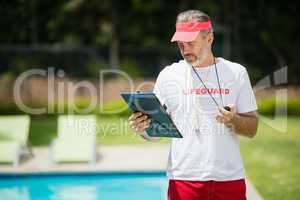 Swim coach looking at clipboard near poolside