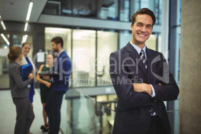 Portrait of businessman standing with arms crossed in corridor