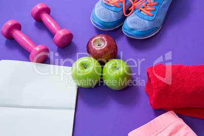 Fitness accessories with opened book and apples