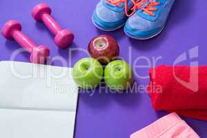 Fitness accessories with opened book and apples