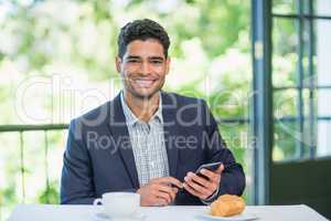 Happy businessman holding mobile phone