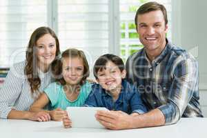 Smiling family using digital tablet in living room at home