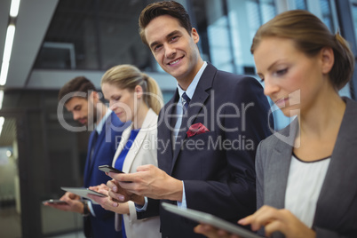 Business executives using electronic devices in corridor