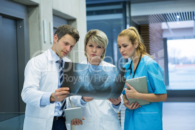 Medical team examining x-ray report in corridor