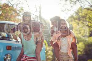 Two couples having piggy ride in park