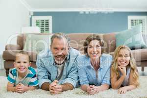 Portrait of smiling family lying together on carpet in living room