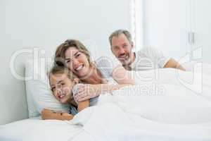 Happy family lying on bed in bedroom at home
