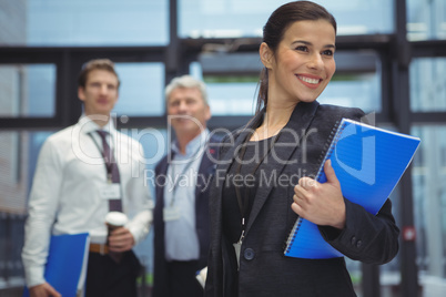 Happy businesswoman standing with spiral book