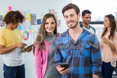 Portrait of happy graphic designers using mobile phone