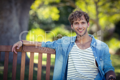 Smiling man sitting on bench in park