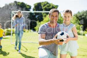 Portrait of smiling father and daughter holding football