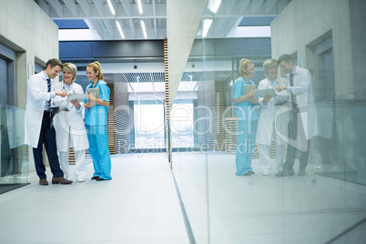 Medical team discussing over digital tablet in corridor