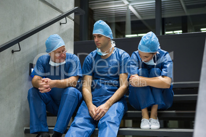 Group of worried surgeons sitting together on staircase